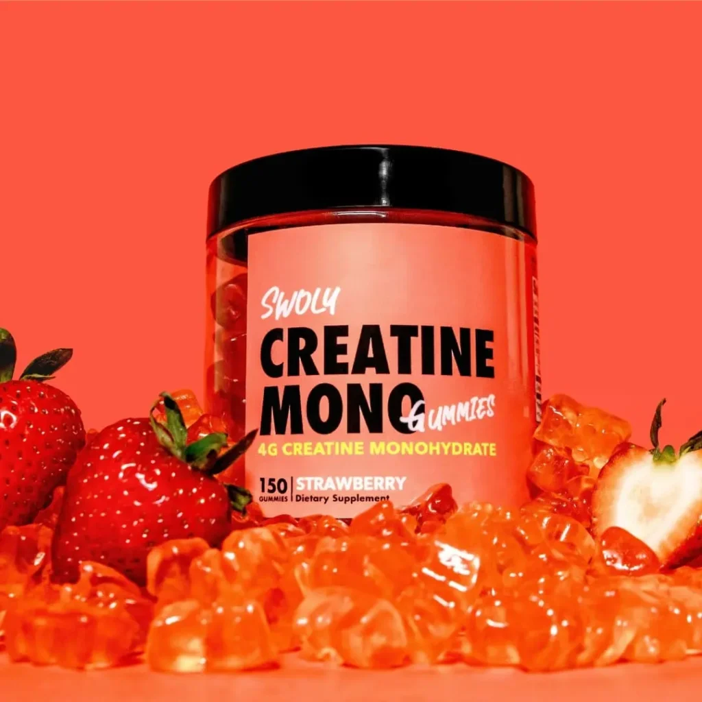 A container of Swoly Creatine Mono Gummies in strawberry flavor, surrounded by fresh strawberries and orange gummies, set against a vibrant red background.